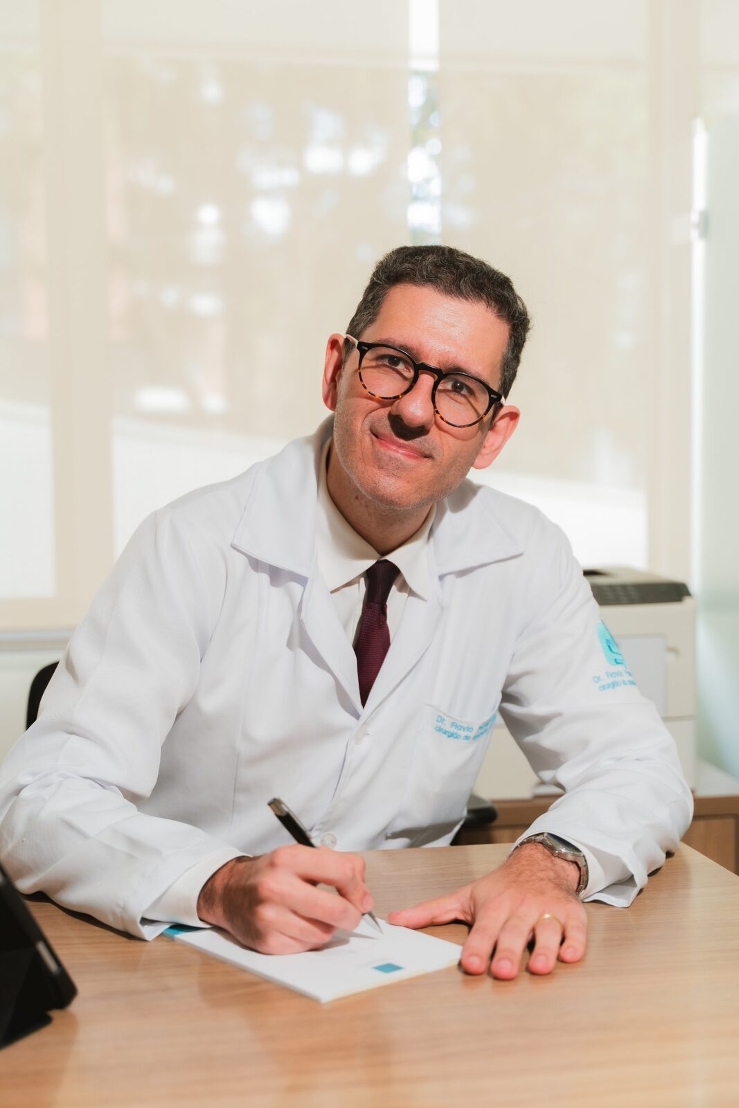 Dr. Flávio de jaleco escrevendo na mesa